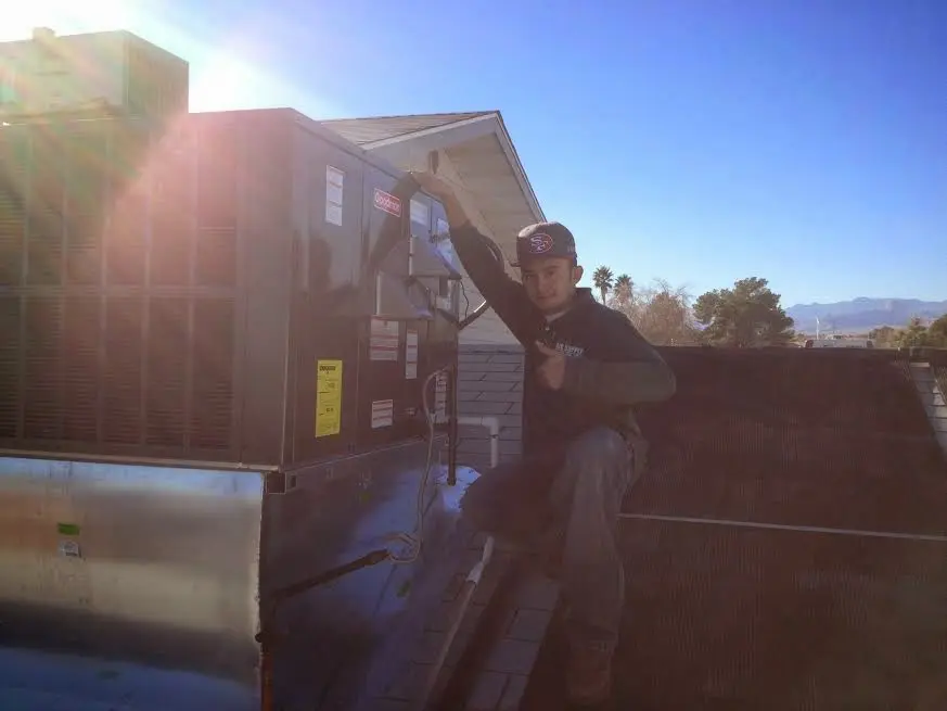 HVAC technician performing Air Duct Cleaning on a rooftop unit in La Marque